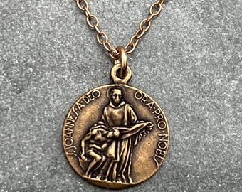 May include: A gold chain necklace with a bronze pendant featuring a religious image of Saint John of God. The pendant has the inscription "JOANNES A DEO ORA PRO NOBIS".