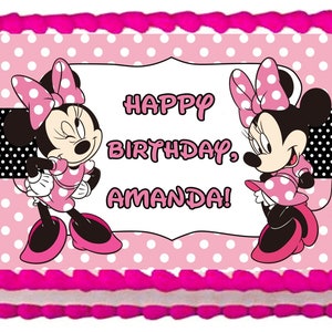 May include: A pink and white polka dot cake with a pink frosting border. The cake is decorated with two images of Minnie Mouse and the text "Happy Birthday, Amanda!"