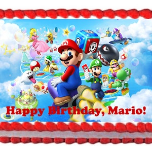 May include: A red and white cake with a frosting border. The cake is decorated with an image of Mario and other characters from the Super Mario Bros. video game series. The image includes a blue sky with clouds, a game board, and the text "Happy Birthday, Mario!"