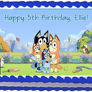 May include: A rectangular cake with a blue border and a light blue image featuring cartoon characters and the text "Happy 5th Birthday, Ellie!". The image shows a family of cartoon dogs in a park setting.