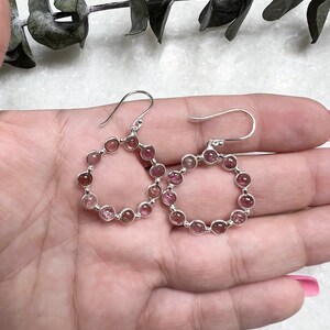 Puede incluir: Un par de pendientes de aro de plata con piedras preciosas rosas y transparentes. Los pendientes est&aacute;n hechos de una delicada cadena de plata con peque&ntilde;as piedras preciosas redondas.