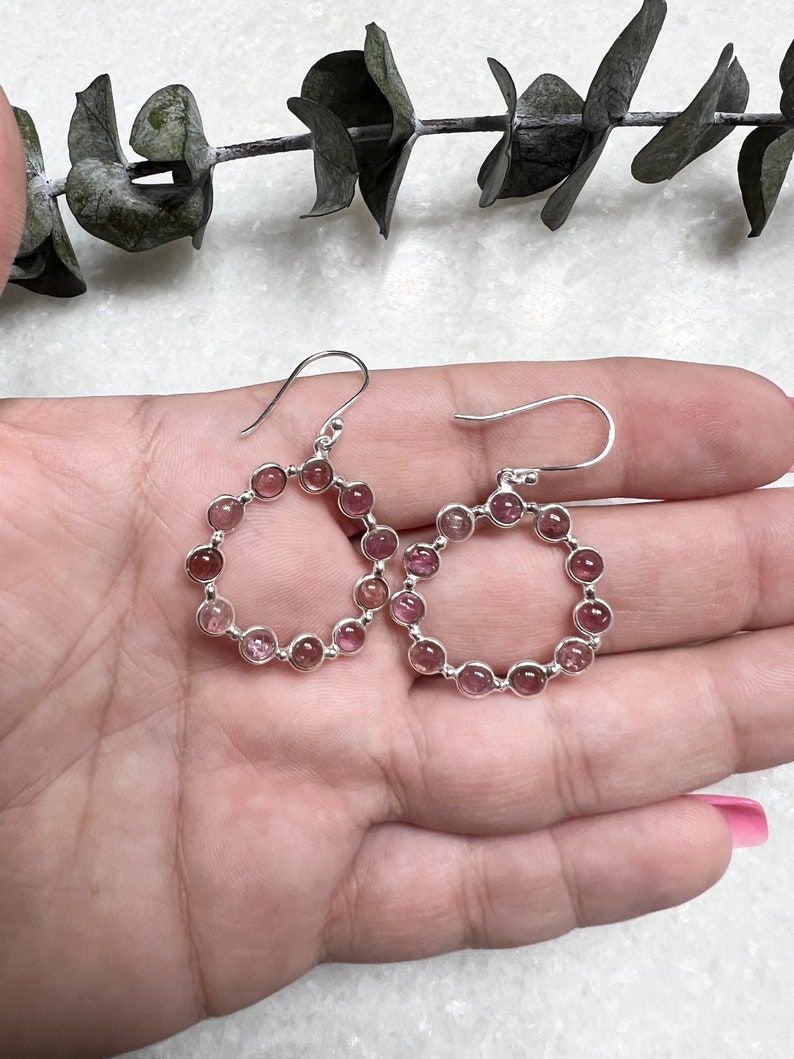 Puede incluir: Un par de pendientes de aro de plata con piedras preciosas rosas y transparentes. Los pendientes est&aacute;n hechos de una delicada cadena de plata con peque&ntilde;as piedras preciosas redondas.