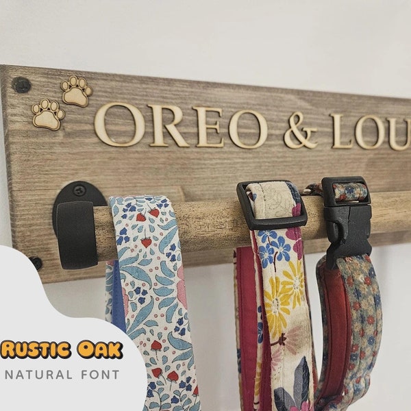 May include: A rustic oak dog leash holder with the names "OREO & LOUIE" in wooden letters. The holder has a wooden dowel for hanging leashes, and includes paw print and bone accents. The leashes have floral and patterned designs.