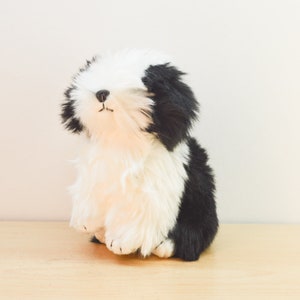 May include: A black and white plush dog toy with a fluffy white body and black fur on its head and back.