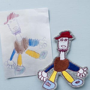 Könnte beinhalten: Eine handgezeichnete Illustration einer Person mit einem roten Hut, einem braunen Hemd, einer blauen Hose und gelben Schuhen befindet sich neben einer Filzapplikation einer Person mit denselben Merkmalen. Die Applikation ist grau mit braunen, blauen, gelben und roten Details.