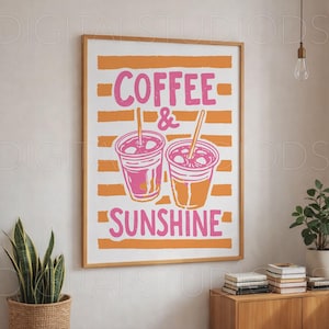 May include: A framed art print with the words "COFFEE & SUNSHINE" in pink, with two coffee cup illustrations. The background features orange horizontal stripes. The print is in a wooden frame and is displayed on a white wall.