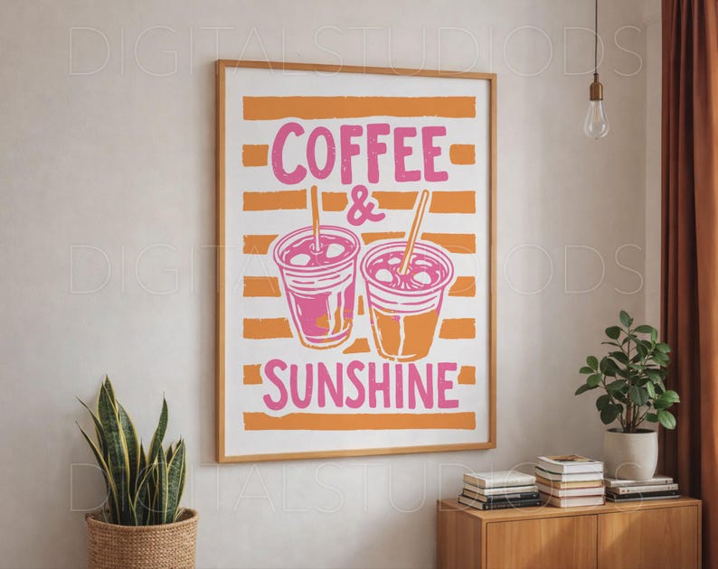 May include: A framed art print with the words "COFFEE & SUNSHINE" in pink, with two coffee cup illustrations. The background features orange horizontal stripes. The print is in a wooden frame and is displayed on a white wall.