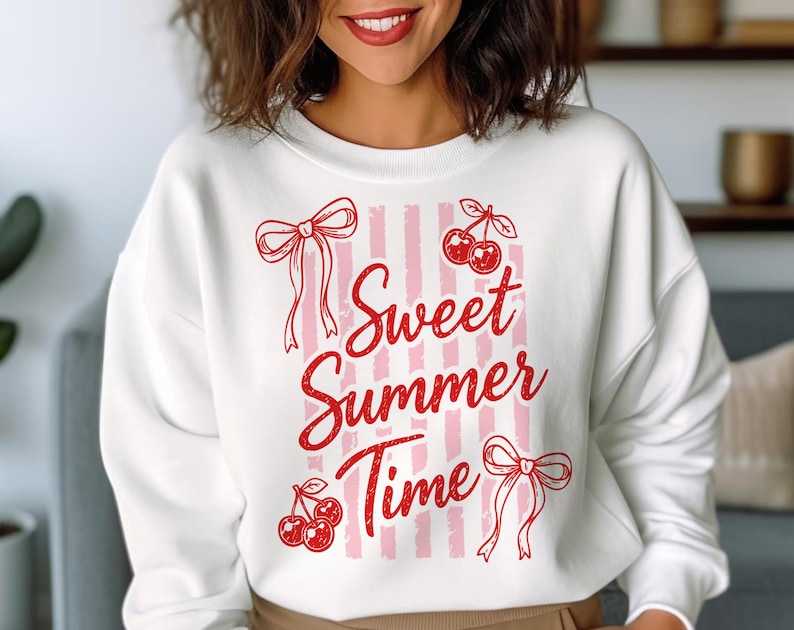May include: White sweatshirt with a red and pink design. The design includes the text "Sweet Summer Time" with cherries and bows. The sweatshirt has a crew neck and long sleeves.