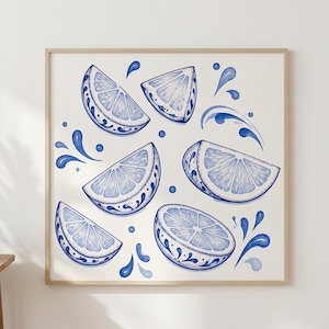 May include: Watercolor print of lemon slices and water splashes in shades of blue. The lemon slices have a decorative border. The artwork is framed in a light wood frame and is displayed on a white wall.