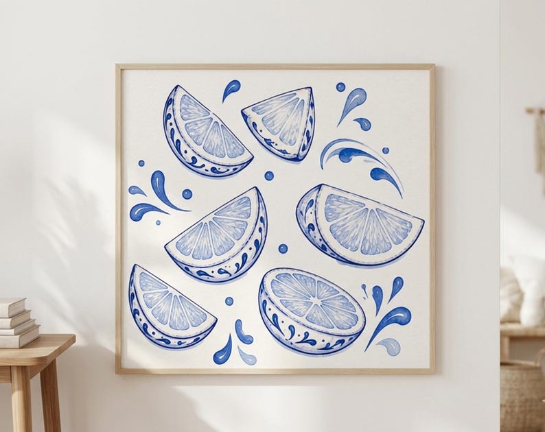 May include: Watercolor print of lemon slices and water splashes in shades of blue. The lemon slices have a decorative border. The artwork is framed in a light wood frame and is displayed on a white wall.