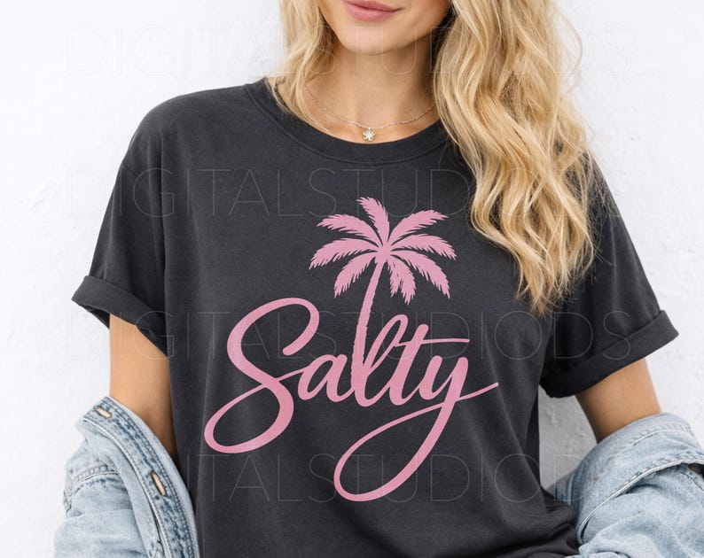 May include: Dark gray t-shirt with a pink palm tree graphic and the word "Salty" in a cursive font. The shirt has rolled-up sleeves and a relaxed fit. The design is centered on the front of the shirt.