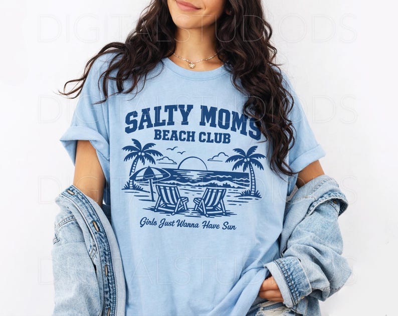 May include: Light blue t-shirt with a graphic that reads "Salty Moms Beach Club" above a beach scene with palm trees, beach chairs, and the text "Girls Just Wanna Have Sun."