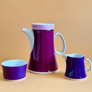Può includere: Un set di tre tazze in ceramica con finitura opaca e macchiettata. Le tazze sono nei toni del crema, grigio chiaro e grigio scuro. Ogni tazza ha un design semplice e minimalista e un manico arrotondato.