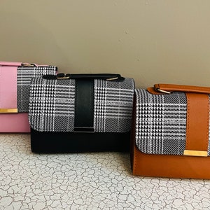 May include: Three small handbags with a black and white plaid pattern. The handbags have a contrasting colored flap and strap. The handbags are pink, black, and brown.