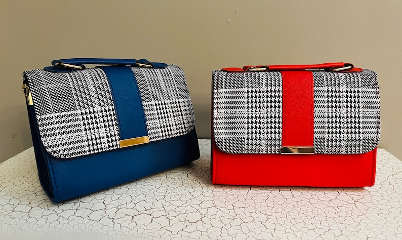 May include: Two small handbags with a plaid pattern on the flap and a solid colored bottom. The handbag on the left is blue and the handbag on the right is red.