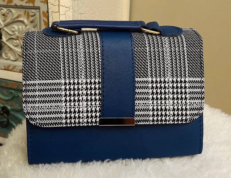 May include: A small blue and white plaid handbag with a gold clasp and a blue leather bottom.