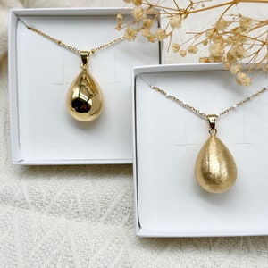 Gold pregnancy bola in the shape of a drop