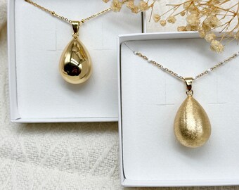 Gold pregnancy bola in the shape of a drop
