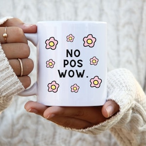 May include: White ceramic mug with a black and white graphic that says "NO POS WOW."  The graphic is surrounded by pink flowers with yellow centres.