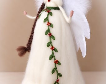 May include: A needle-felted angel figurine with brown hair in a long braid, wearing a white dress adorned with a green vine featuring small red berries. The angel has large white feathered wings, a matching floral headband, and a small red berry accent at the neckline.