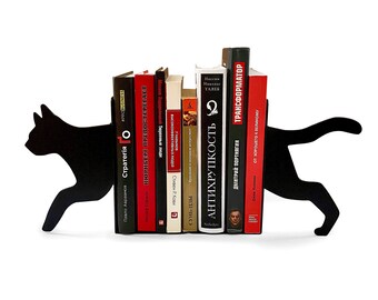 Pode incluir: Separadores de livros de metal preto em forma de gato segurando uma pilha de livros. Os livros têm títulos em russo e incluem "Стратегия", "Нюрнберг Предостерегает", "Антихрупкость", "Трансформатор", e "От Хорошего К Великому".