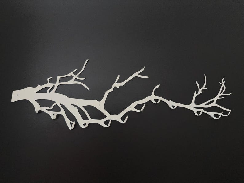 May include: A white metal wall art piece in the shape of a tree branch, with multiple offshoots and a textured surface. The branch is mounted on a black background, creating a striking contrast. This decorative piece is ideal for adding a natural element to any room.