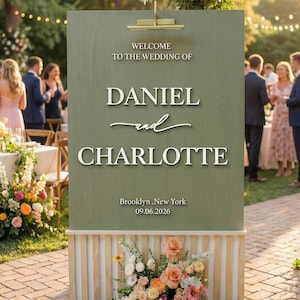 May include: A handmade wooden sign with the text "Welcome" in a playful font. The sign is painted white with a distressed finish, and features a decorative floral design in shades of pink and green. It measures approximately 12 inches wide.