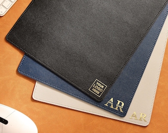 May include: Three leather mousepads in black, blue, and beige. The black mousepad has a gold square with the text "YOUR LOGO HERE". The blue mousepad has a gold square with the text "AR Adam Russell". The beige mousepad has a gold square with the text "AR".