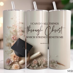 May include: A beige tumbler with a straw, featuring floral accents and a graduation cap. The text reads "I CAN DO ALL THINGS THROUGH CHRIST WHICH STRENGTHENETH ME" from Philippians 4:13. The design includes a scroll.