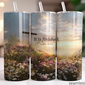 May include: A set of three stainless steel tumblers with a wraparound design featuring a cross, a field of flowers, and a sunset sky. The text "It is finished. John 19:30" is printed on the tumbler.