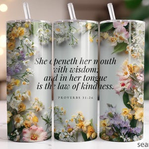 May include: A floral tumbler with a straw, featuring a design of colorful flowers and the text "She openeth her mouth with wisdom, and in her tongue is the law of kindness. PROVERBS 31:26."