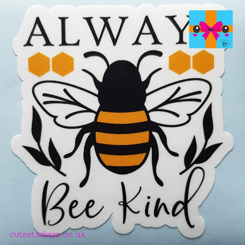 May include: A white sticker with a black and yellow bee illustration. The words "ALWAYS Bee Kind" are written in black script. The sticker also features orange honeycomb shapes and black leaf accents.