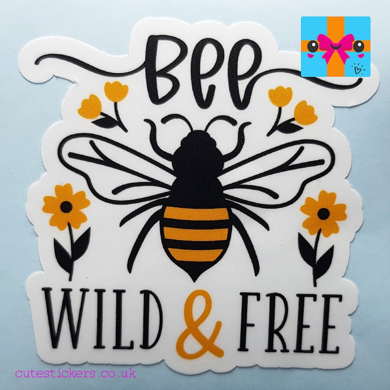 May include: A white sticker featuring a black and yellow bee illustration with the words "BEE WILD & FREE" in black and orange. The design includes yellow flowers. The website address cutestickers.co.uk is at the bottom.