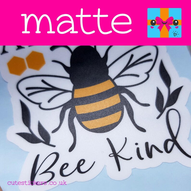 May include: A matte sticker featuring a black and yellow bee with the words "Bee Kind" in cursive. The sticker also includes black leaf and honeycomb designs. The word "matte" is at the top in white letters.