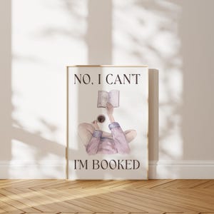 May include: A framed print with the text "NO, I CAN'T I'M BOOKED". The artwork depicts a person reclining, holding a book and a coffee cup. The illustration is in soft watercolor tones, with a neutral background.