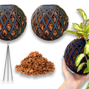 May include: Two black hanging planters with a diamond pattern and coconut fiber lining. A pile of coconut fiber is in the center of the image. A third planter is shown with a green and white plant inside.