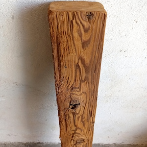 Peut inclure: Gros plan sur une poutre en bois vieillie de couleur brune avec un n&oelig;ud et un motif de grain. La poutre est brute et a un aspect rustique.