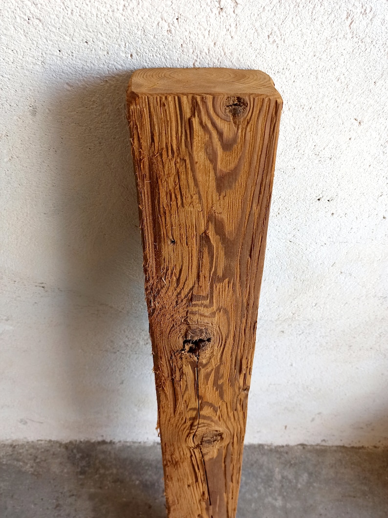 Peut inclure: Gros plan sur une poutre en bois vieillie de couleur brune avec un n&oelig;ud et un motif de grain. La poutre est brute et a un aspect rustique.