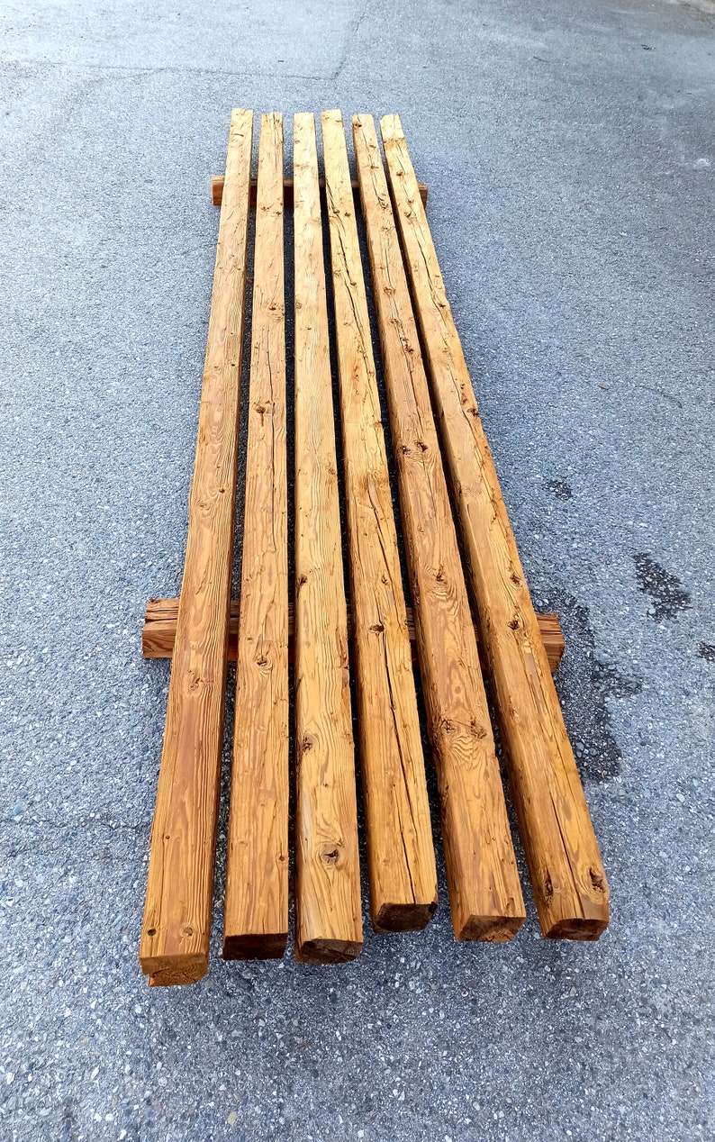 Peut inclure: Une pile de huit poutres en bois de r&eacute;cup&eacute;ration, chacune mesurant environ 3 m&egrave;tres de long et 15 cm de large, avec une couleur brun naturel et une texture rugueuse et patin&eacute;e.