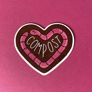 May include: A brown heart-shaped sticker with a pink worm curled around the outside. The worm has a smiling face and the word "COMPOST" is written inside the heart.