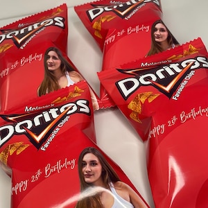 May include: Multiple red Doritos chip packets, each with a custom image and the text "Happy 25th Birthday." The packets display the Doritos logo and the words "Favourite Chips."
