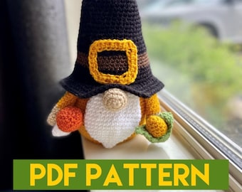 Pode incluir: Padrão de crochê para um gnomo de Ação de Graças usando um chapéu preto com uma fivela marrom e amarela, segurando uma pequena abóbora laranja e verde. Padrão PDF.