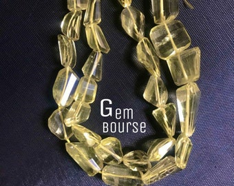 May include: Two strands of faceted, light yellow gemstone beads with a yellow tassel, against a dark blue background. The beads are strung together, and the text "Gem Bourse" is visible.