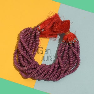 May include: A strand of purple gemstone beads with a red tassel. The beads are round and smooth, and the tassel is made of soft, fluffy fibers.