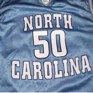 May include: A light blue basketball jersey with white lettering that reads "NORTH CAROLINA" and the number "50".