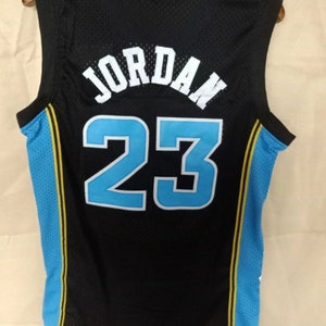 May include: Black basketball jersey with blue and yellow trim. The back of the jersey has the name "JORDAN" and the number "23" in white.