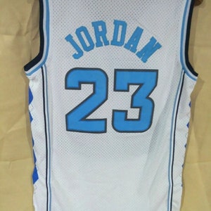 May include: White basketball jersey with blue and black trim. The back of the jersey has the name "JORDAN" and the number "23" in blue.