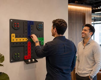 May include: A wall-mounted board game featuring a dark gray square base with four colored paths in yellow, blue, green, and red. Each path has matching colored pegs and a small tray at the bottom holding two white dice with black pips.