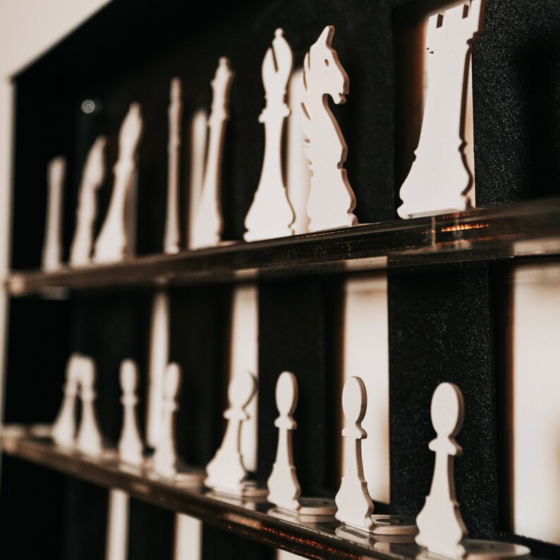 May include: White chess pieces arranged on a black and white checkered board. The pieces are made of wood and are in various sizes and shapes. The board is made of wood and has a black and white checkered pattern.
