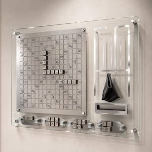 May include: A wall-mounted game board featuring a metallic grid with letter tiles spelling WEAR, SHELF, and MOVE. The board includes a vertical rack with a black pouch, a horizontal slot, and four lower sections holding additional letter tiles.